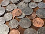 A bunch of US currency coins in a pile on a desk.